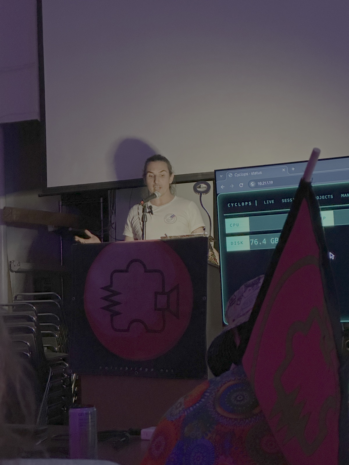 Marco giving a talk at Noisebridge, with the Cyclops status screen beside the lectern